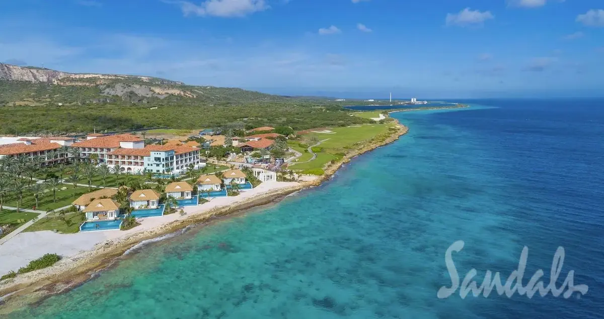 Aerial view of Sandals Royal Curaçao coastline with seaside bungalows and turquoise Caribbean water